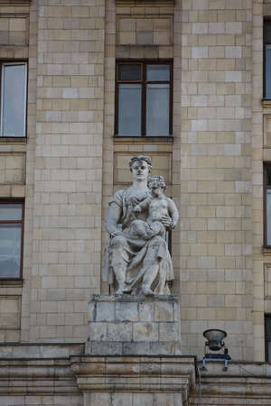 MOSCOW / RUSSIA - 20/04/2019 soviet communist stone sculpture of a sitting mother holding a baby child (sculptors Baburin, Nikogosyan, Anikushin) Kudrinskaya Square Building (Aviators' House) facade.のeditorial素材