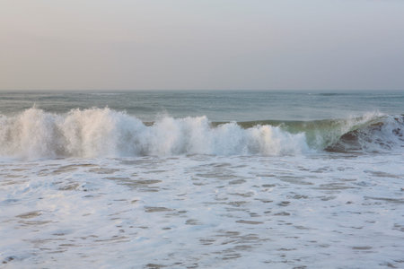 natural copy space shot of a wave crushing on the smooth yellow sand beach surface, forming white...