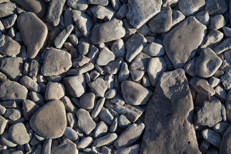 filled frame close up background wallpaper shot of gray cobble rock stones on a beach surface