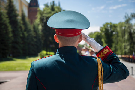 MOSCOW, RUSSIA - 06/23/2020: Young sailor soldier from Preobrazhensky Life Guards Regiment doing a military salute by the Eternal Flame at the Tomb of Unknown Soldier, Alexander garden. Shot from backのeditorial素材