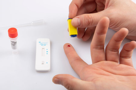 isolated shot of two a hand with a lancet taking a blood sample from finger and a blank rapid...