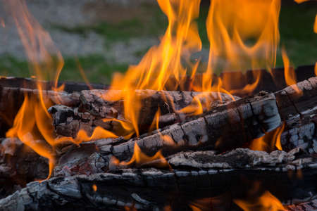 close up shot of log pieces and fire wood, charcoal and ashes burning in a hot oranges flames in an old vintage brazierの写真素材