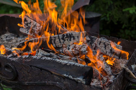 close up shot of log pieces and fire wood, charcoal and ashes burning in a hot oranges flames in an old vintage brazierの写真素材