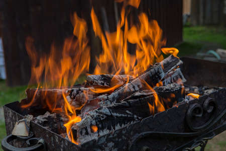 close up shot of log pieces and fire wood, charcoal and ashes burning in a hot oranges flames in an old vintage brazierの写真素材