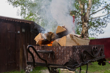 close up shot of log pieces and fire wood, charcoal and ashes burning in hot oranges flames in an old vintage brazierの写真素材