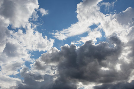 beautiful day cloudscape view from below of fluffy dramatic white and gray clouds on a deep blue sky...