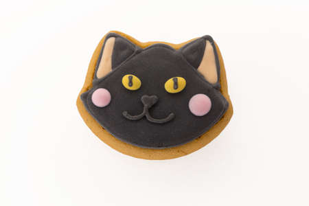 Halloween gingerbread cookie with icing in shape of a black cat. Isolated close up top view shot on a white backgroundの写真素材