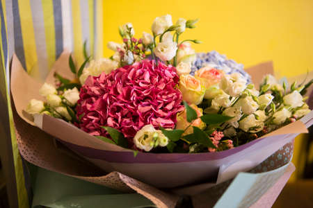 beautiful bouquet with pink and blue Hydrangea Hortensia flowers, white and yellow roses, in paper wrap side view close upの写真素材