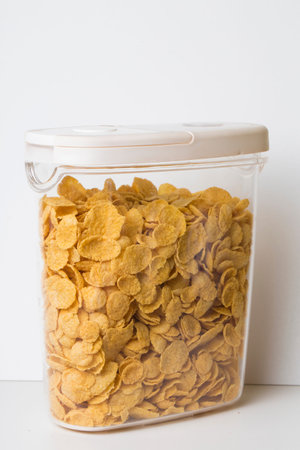 corn flakes in a plastic food container jar with white lid isolated on white background