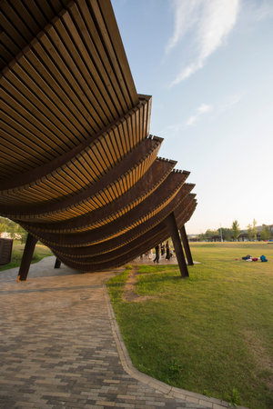 Moscow, Russia 08.08.2021 modern brown wooden pergola with people dancing under roofed section....