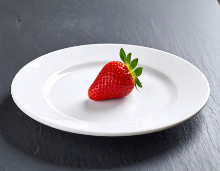 A single fresh red strawberry fruit on white plate. simple healthy food with minimalist feeling, perfect clean organic snack for dietの素材
