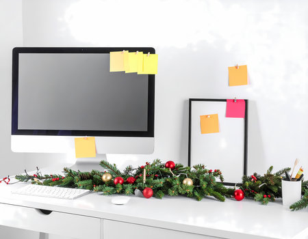 A cheerful office desk with computer and festive christmas holiday decoration. modern workspace ready for celebration with blank screen for copyの素材