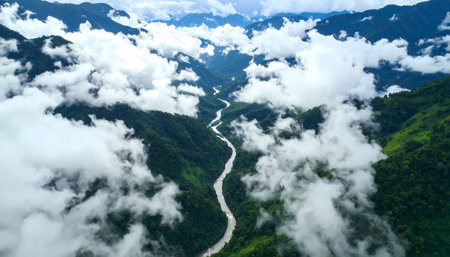 A majestic aerial view from above cloud of winding river flowing through deep green valley and mountain. breathtaking and tranquil landscape from high altitude perspectiveの素材