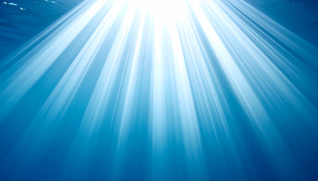 Serene underwater background of deep blue sea or ocean. Beautiful light and sunbeam rays shine down from surface, creating hopeful and peaceful abstract sceneの素材