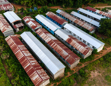Aerial view of rural housing camp showing barrack with rusty metal roof. dilapidated building shows stark reality of life in developing settlementの素材