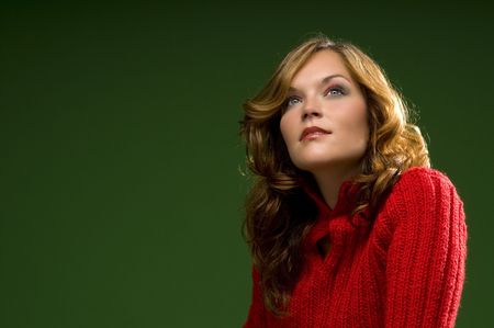 Dark blond beauty awaiting on Christmas green background with red sweaterの写真素材