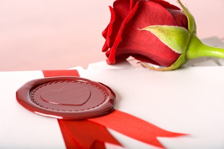 Red rose and love-letter with seal lying on keyboardの写真素材