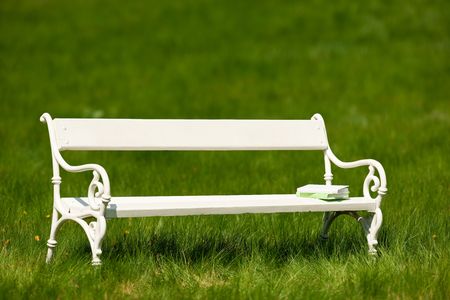 White bench with books in green meadow shallow DOFの写真素材