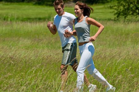 Young man and woman jogging in a meadow, shallow DOFの写真素材