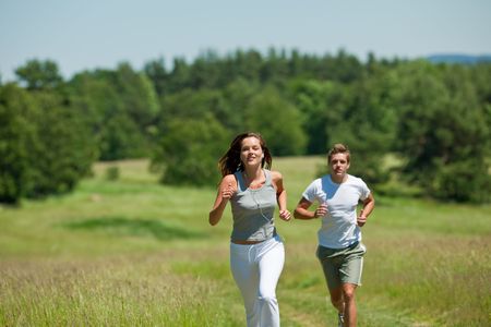 Brown hair woman with headphones jogging, man in bakcground, shallow DOFの写真素材