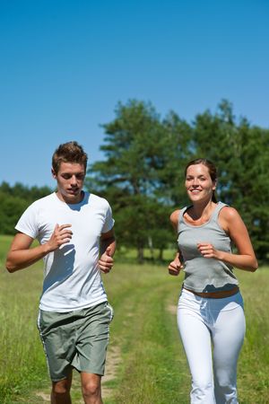 Sportive man and woman jogging outdoors, shallow DOFの写真素材