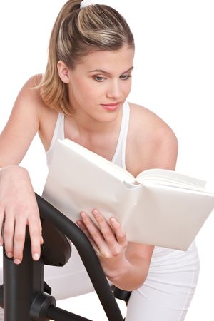 Fitness series - Woman reading book cycling on exercise bikeの写真素材