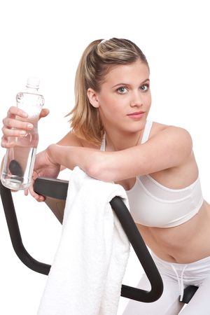 Fitness series - Woman with exercise bike  and bottle of water on white backgroundの写真素材