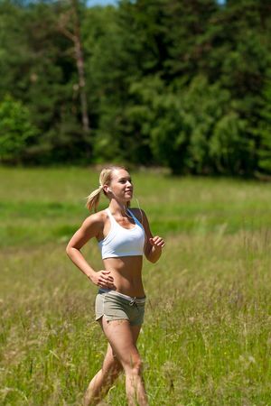 Young woman jogging in a meadow on a sunny dayの写真素材