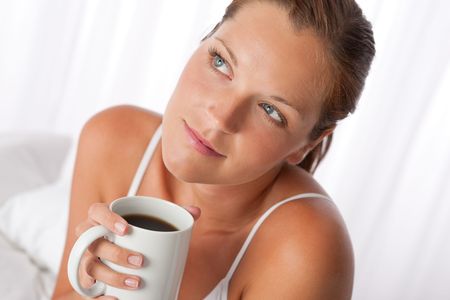 Beautiful young woman holding  white cup of coffee homeの写真素材