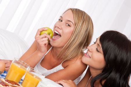 Blond woman and brunette having breakfast in bedの写真素材