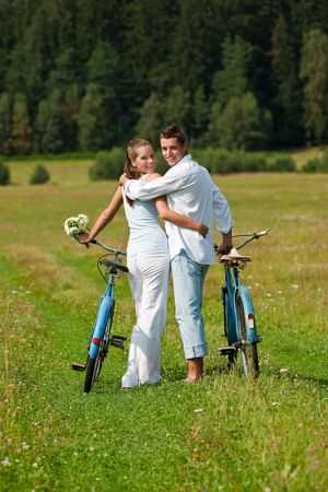 Romantic couple walking with old-fashioned bike in meadow on sunny dayの写真素材