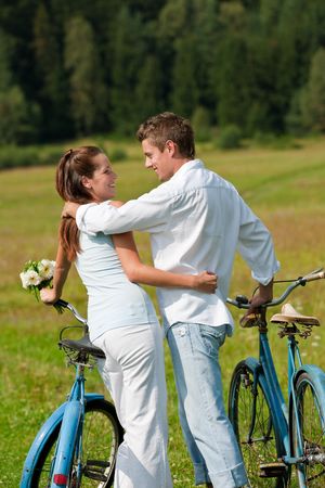 Romantic couple walking with old-fashioned bike in meadow on sunny dayの写真素材