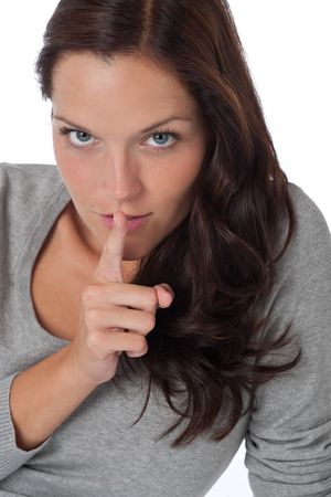 Beautiful woman expressing silence, finger on lips, on white backgroundの写真素材