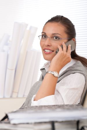 Young businesswoman on the phone sitting at officeの写真素材