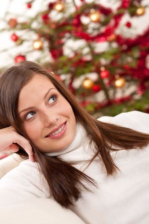 Smiling young woman in front of Christmas tree sittingの写真素材