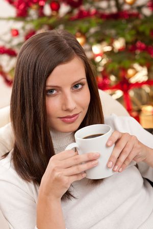 Brown hair woman relaxing with coffee on Christmas in front of Christmas treeの写真素材