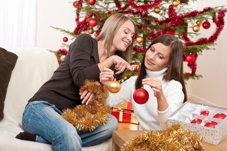 Two smiling women with Christmas decoration, chains and ballsの写真素材