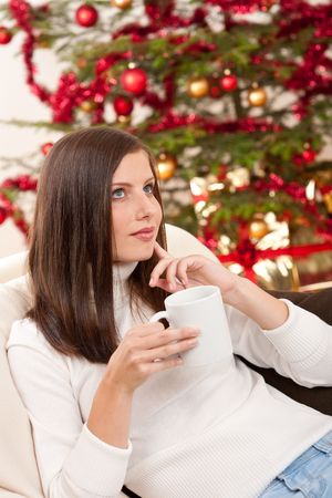 Brown hair woman relaxing with coffee on Christmas in front of Christmas treeの写真素材