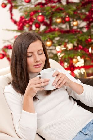 Brown hair woman relaxing with coffee on Christmas in front of Christmas treeの写真素材