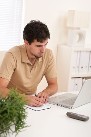 Young modern businessman with laptop sitting at the officeの写真素材