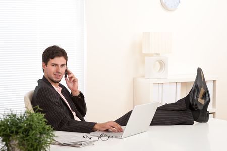 Young businessman on the phone with legs upの写真素材