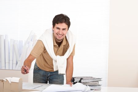 Young male architect working with plans and architectural model at officeの写真素材