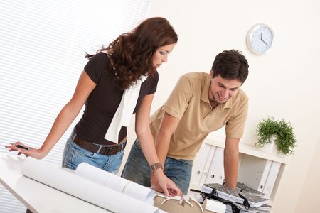 Young man and woman working at architect office with plansの写真素材