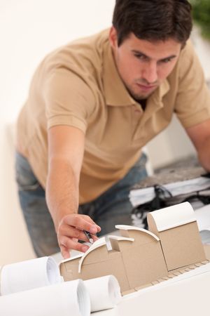 Young male architect working with plans and architectural model at officeの写真素材