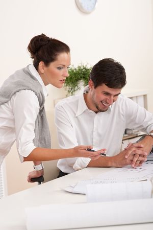 Young man and woman working together at the officeの写真素材