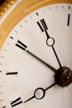 Close-up of antique white and gold clock with Roman numeral, macro lens