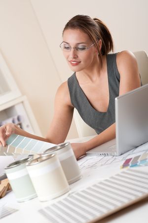 Young female designer working at office with laptop and color swatchの写真素材