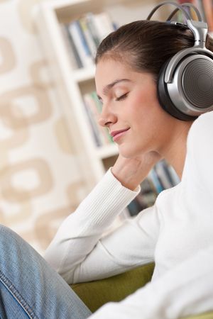 Students - Happy female teenager with headphones listening to music in modern loungeの写真素材