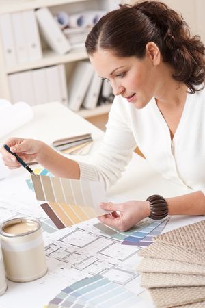 Young female interior designer working at office with color swatch and can of paintの写真素材