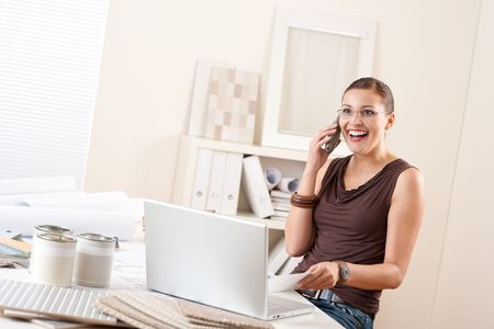 Young female designer on the phone at office with laptop and color swatchの写真素材